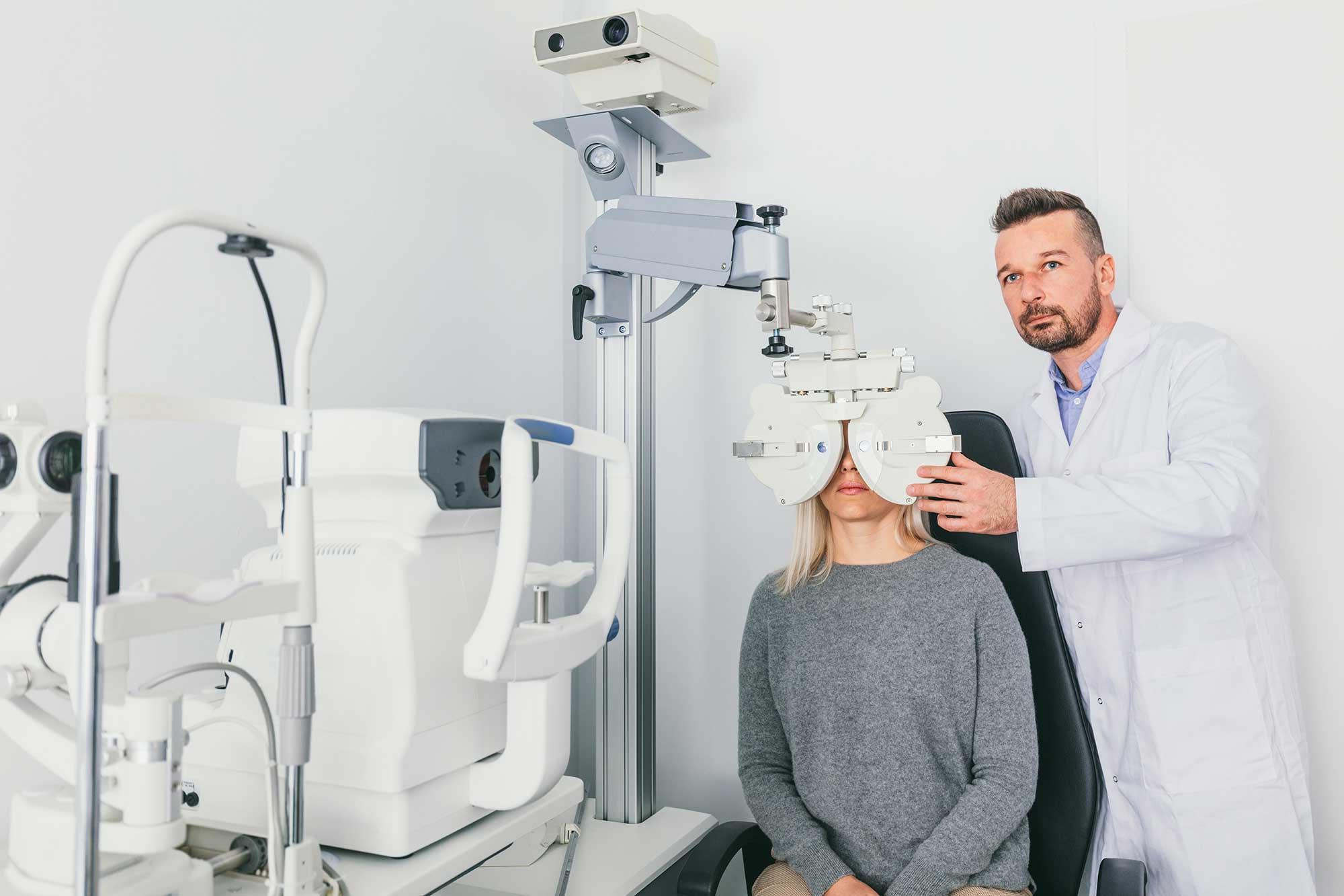 A man and woman are attentively reviewing an eye exam chart together in a clinical setting.