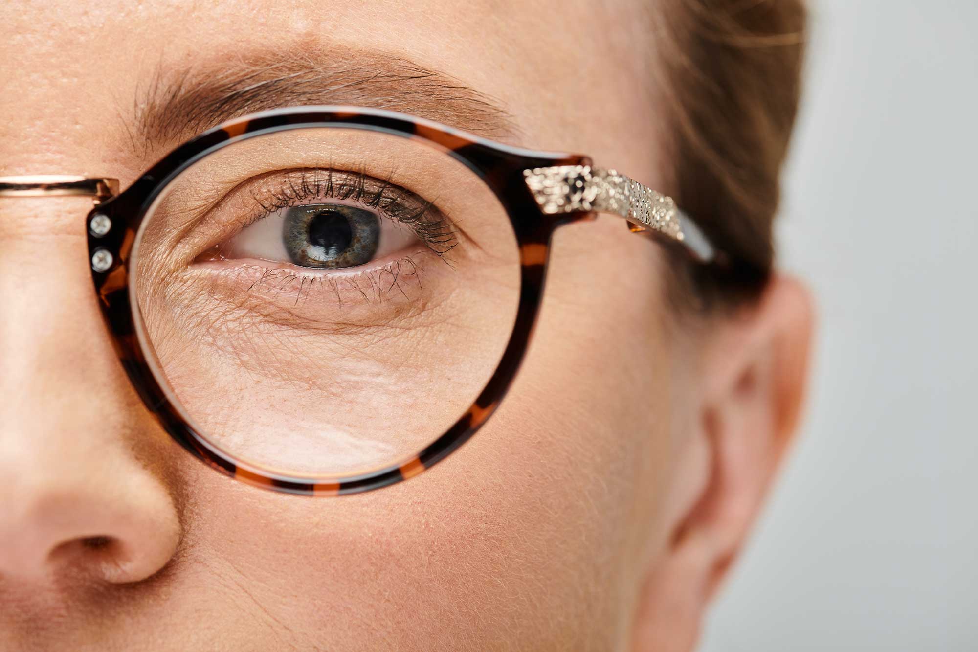 A woman with glasses, showcasing her striking blue eye, gazes thoughtfully at the camera.