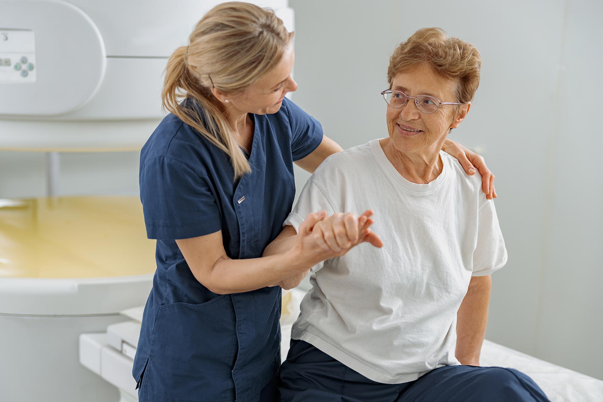 A woman assists an older woman by supporting her arm as they walk together.