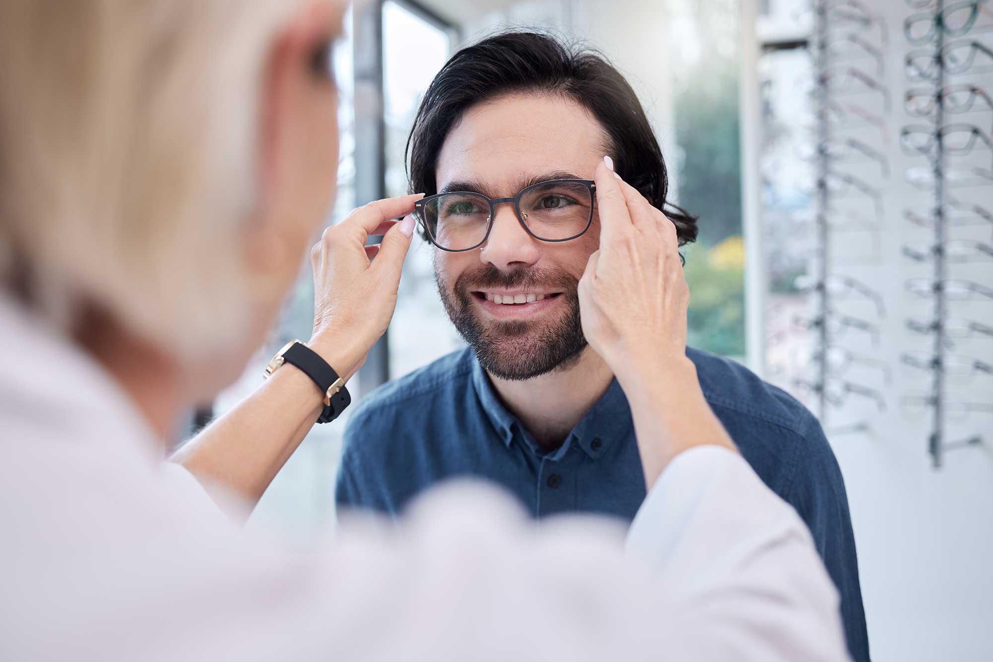 Eye care professional helping patient choose blue light protection glasses for digital screen use.
