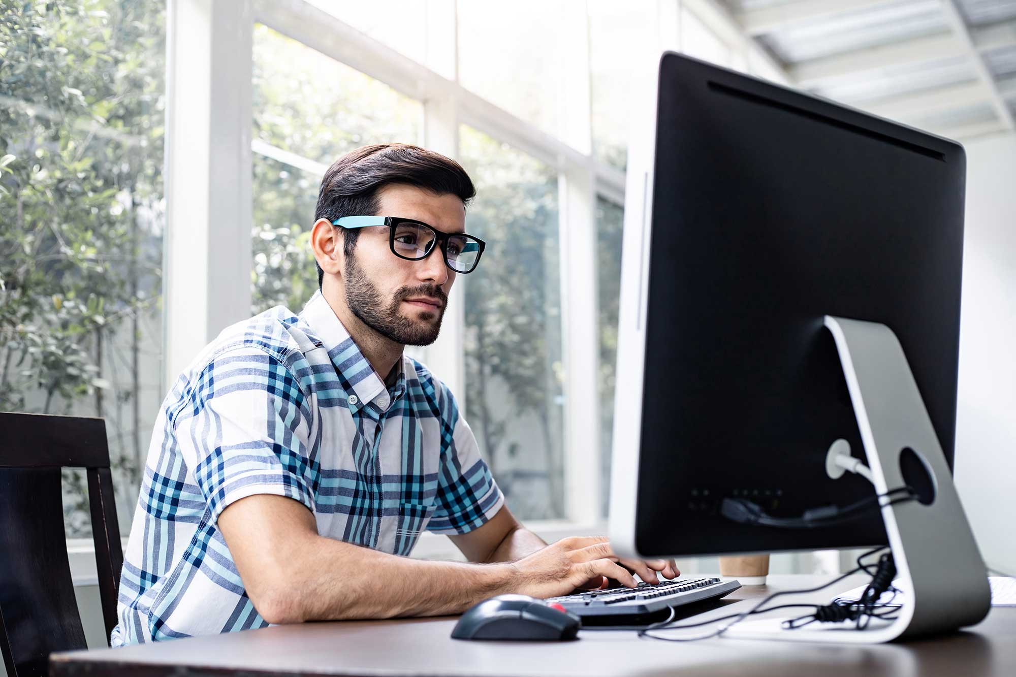 Man focused on screen, using blue light protection glasses to reduce digital strain.